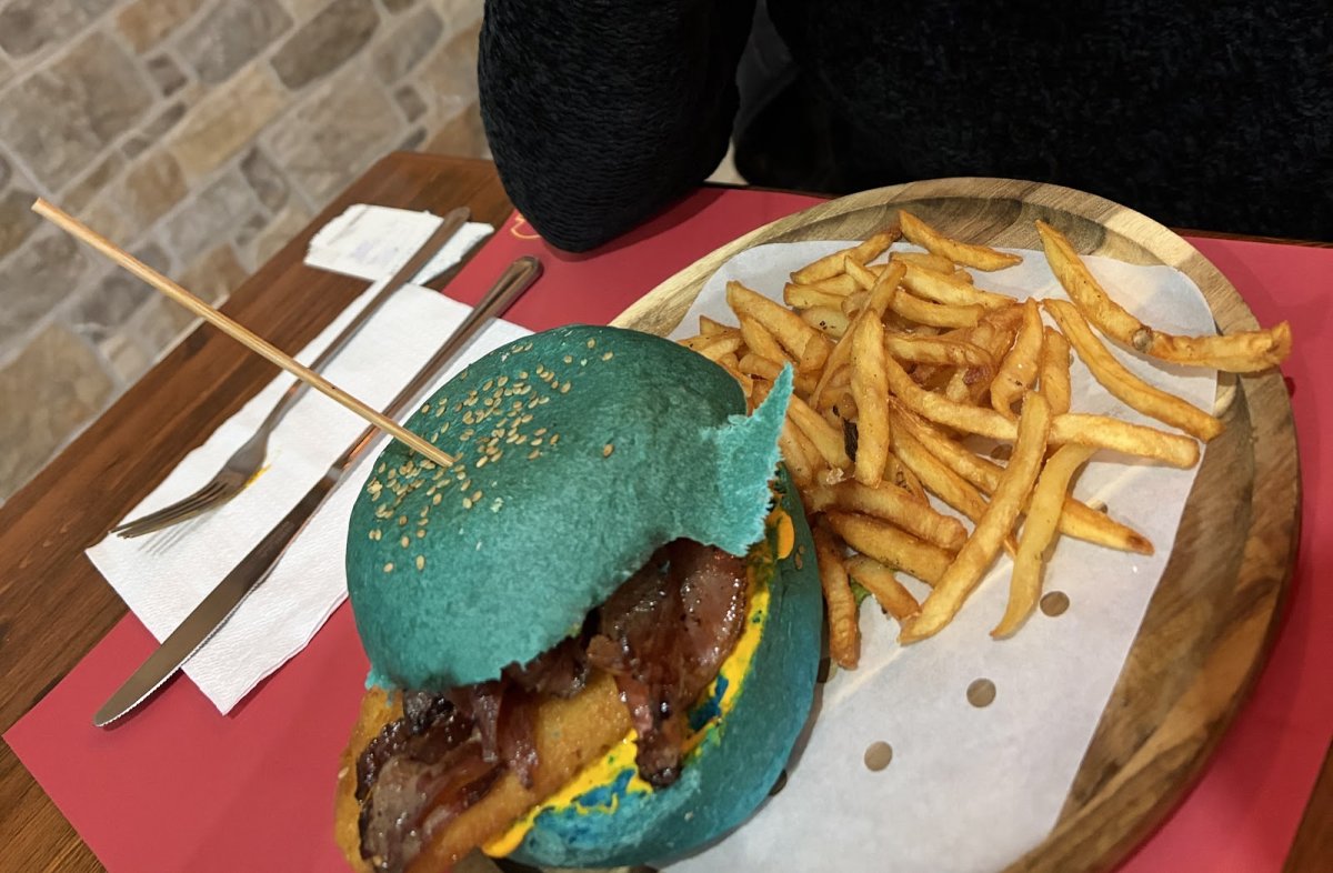 Il panino Warblade con pane blu, hamburger, bacon e rösti, con patatine fritte al pub Dragon Legend di Roma