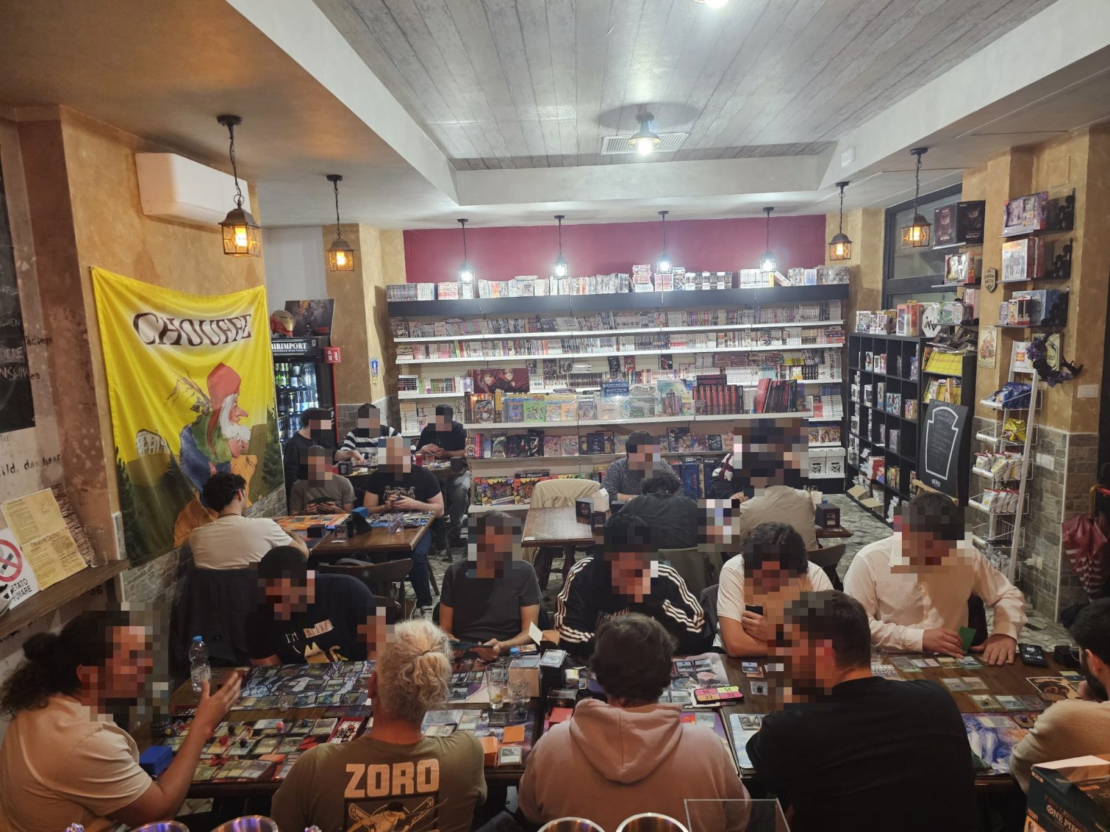 Serata di torneo da Dragon Legend a Roma: sala piena di giocatori tra scaffali di fumetti e giochi
